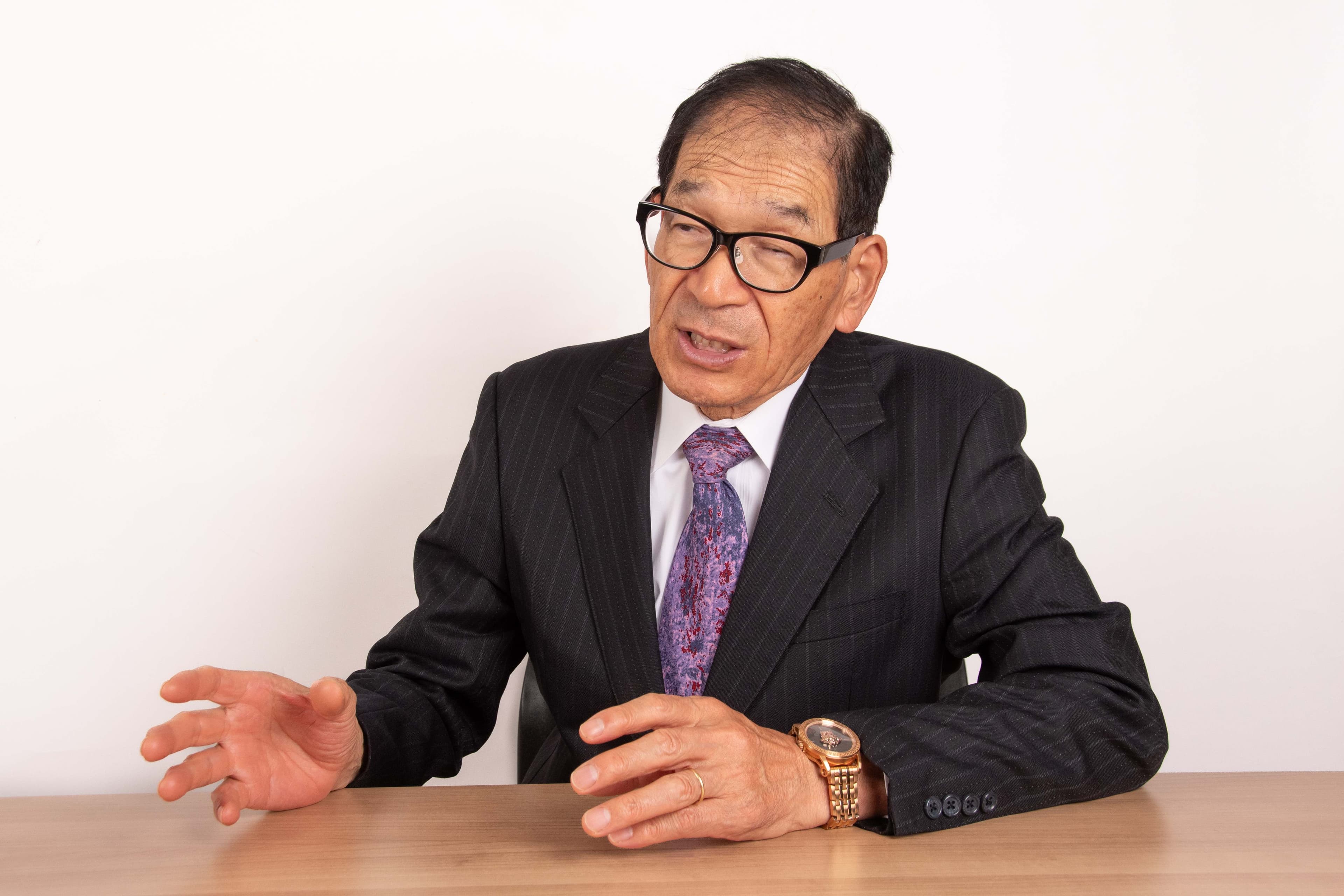 肥本 - 机で手振りを交えながら対話する様子